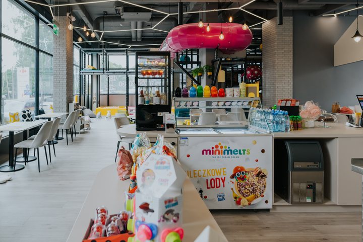 Bar z lodami Mini Melts, witryną z napojami i różową rurą-zjeżdżalnią w tle