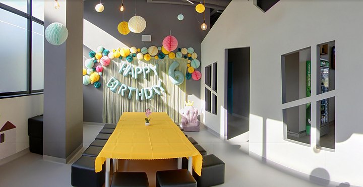 Salka urodzinowa z żółtym stołem, papierowymi kulami i napisem Happy Birthday